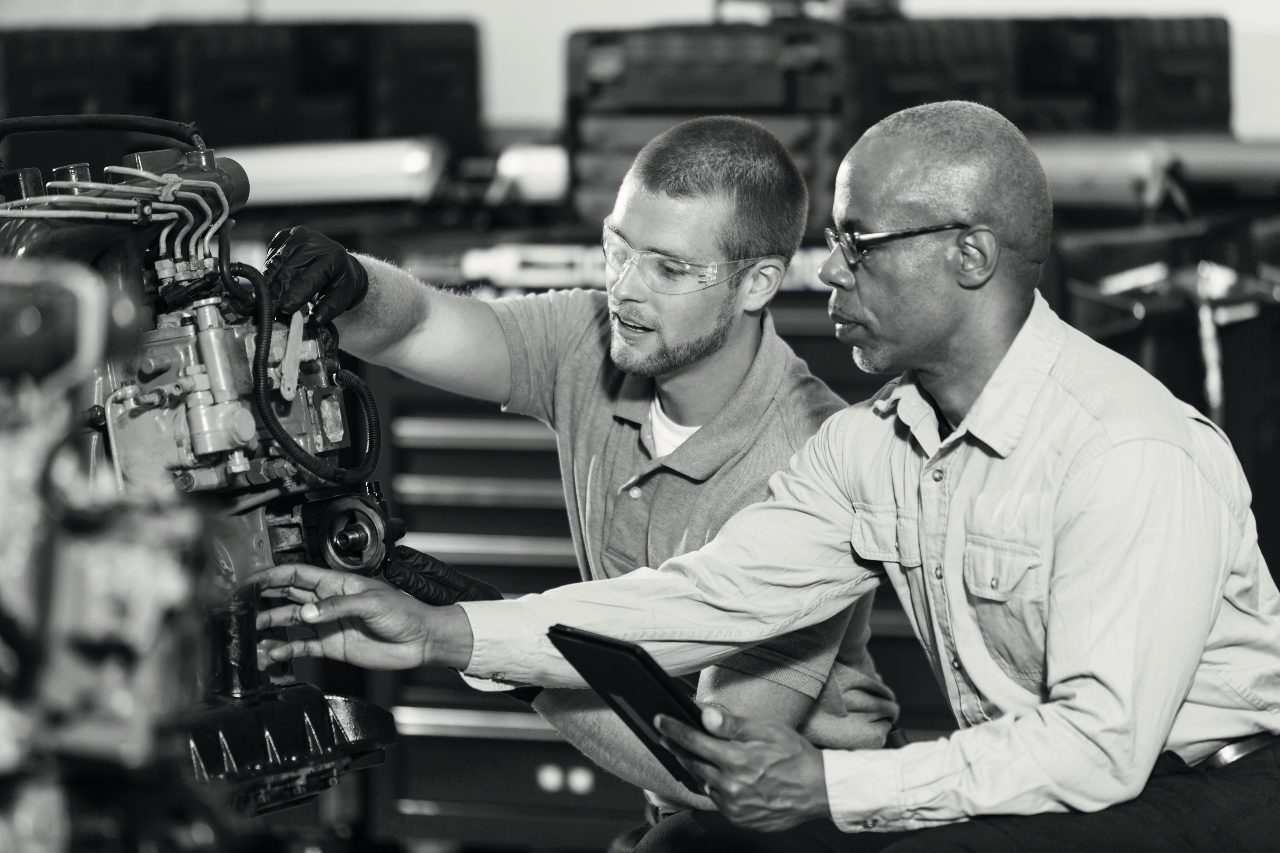 two mechanics inspect a heavy vehicle engine